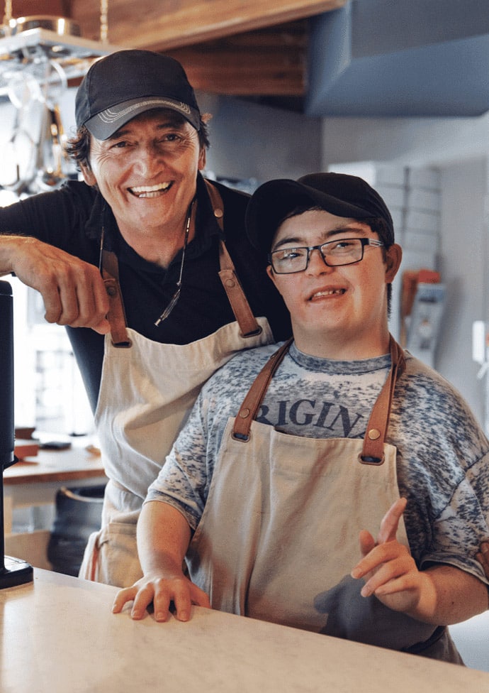 Sozialassistent steht neben Kind mit Down-Syndrom