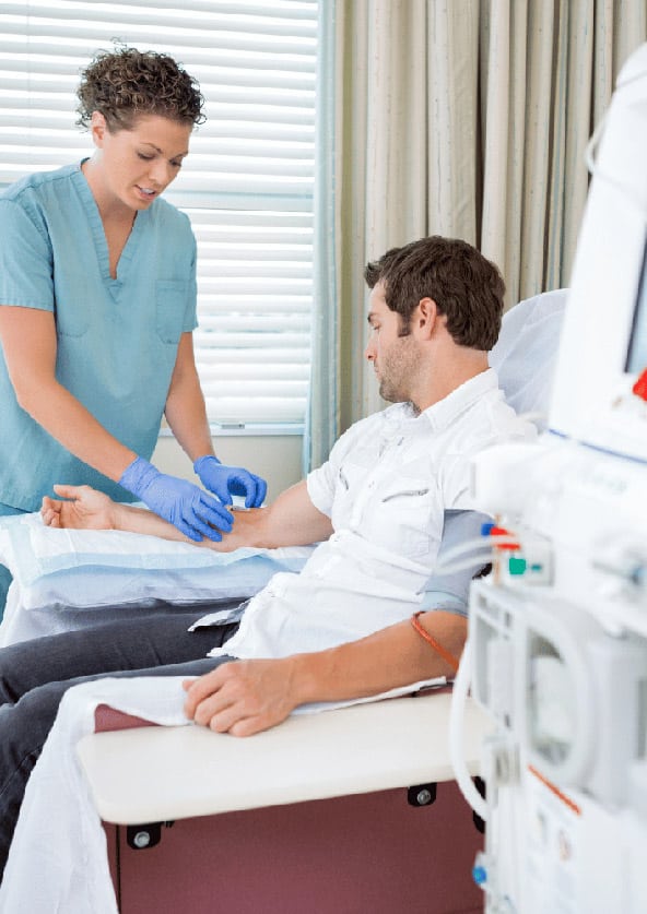 Dialysepflegerin wechselt Kanüle an Dialysepatienten
