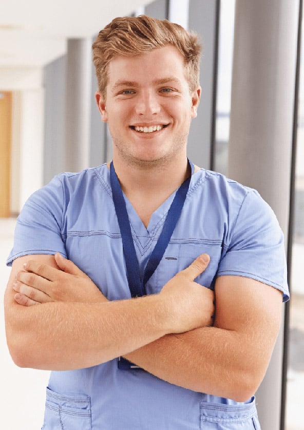 Blonder Pflegeassistent in Krankenhauskleidung lächeln in die Kamera